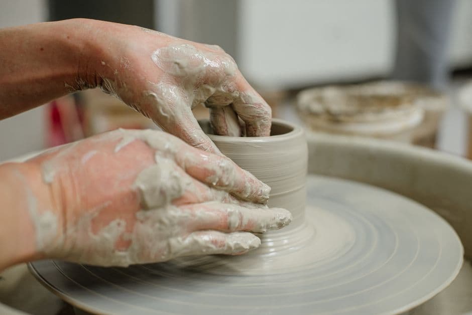 Close-up of Sofia's hands centring wet clay on a spinning pottery wheel